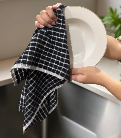 Midnight Black Grid Terry Tea Towel being used to dry a white plate.
